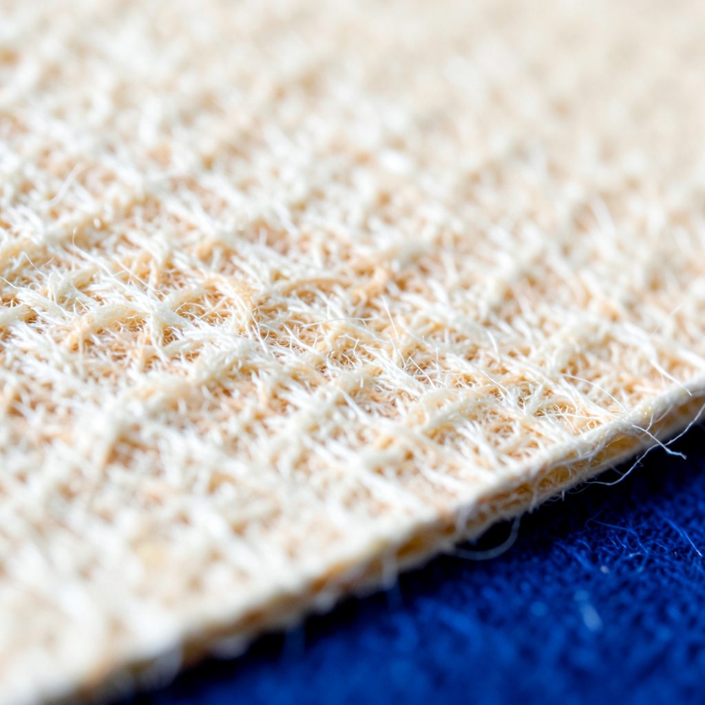 Close-up of textured paper fibers in cream and warm beige tones, soft and tactile